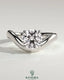 Kynora CJ 2ct round East-West claw solitaire engagement ring with wave band showcasing a sparkling central diamond.