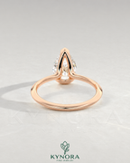 Pear cut moissanite half-bezel engagement ring in 925 silver with a sleek design, displayed on an ivory backdrop.