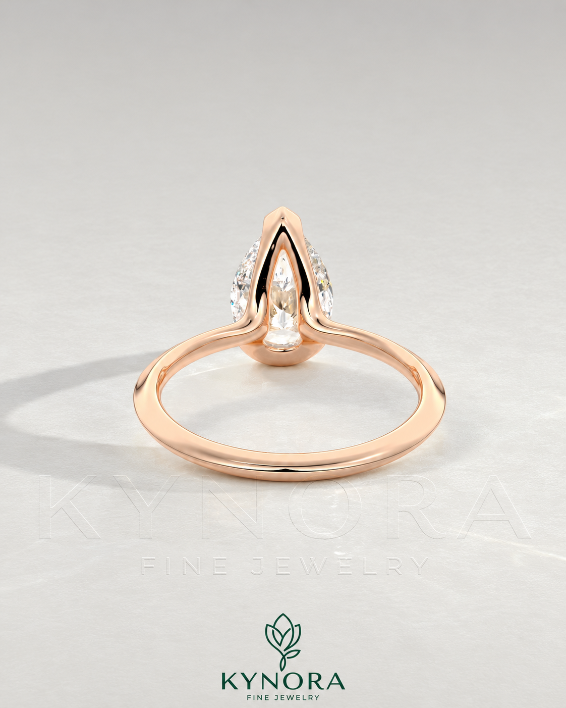 Pear cut moissanite half-bezel engagement ring in 925 silver with a sleek design, displayed on an ivory backdrop.