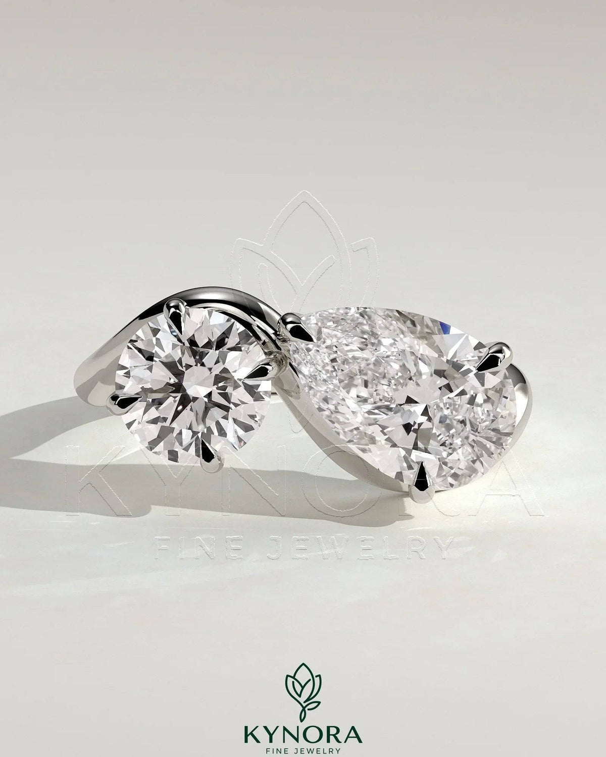 Kynora CJ Toi et Moi engagement ring with 1ct round and 1.5ct pear-shaped diamonds on a wave band. Imagen principal del producto
