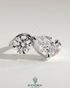 Kynora CJ Toi et Moi engagement ring with 1ct round and 1.5ct pear-shaped diamonds on a wave band.