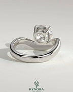 Kynora CJ 2ct round East-West claw solitaire engagement ring with wave band, showcasing a sparkling central diamond.