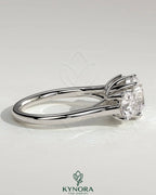Kynora CJ three-stone engagement ring with 2ct round claw trilogy center and round side stones, featuring a trellis gallery design.