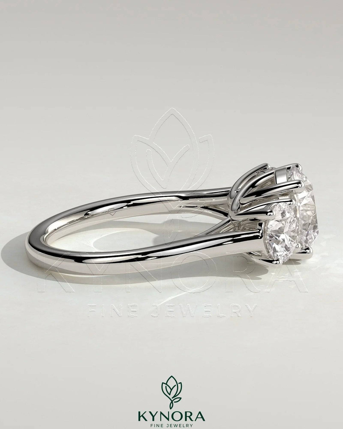 Kynora CJ three-stone engagement ring with 2ct round claw trilogy center and round side stones, featuring a trellis gallery design.