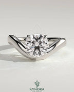 Kynora CJ 2ct round East-West claw solitaire engagement ring with wave band showcasing a sparkling central diamond.