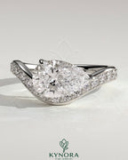 Kynora CJ 2ct pear-shaped diamond solitaire engagement ring with bead-set pave wave band in east-west setting.