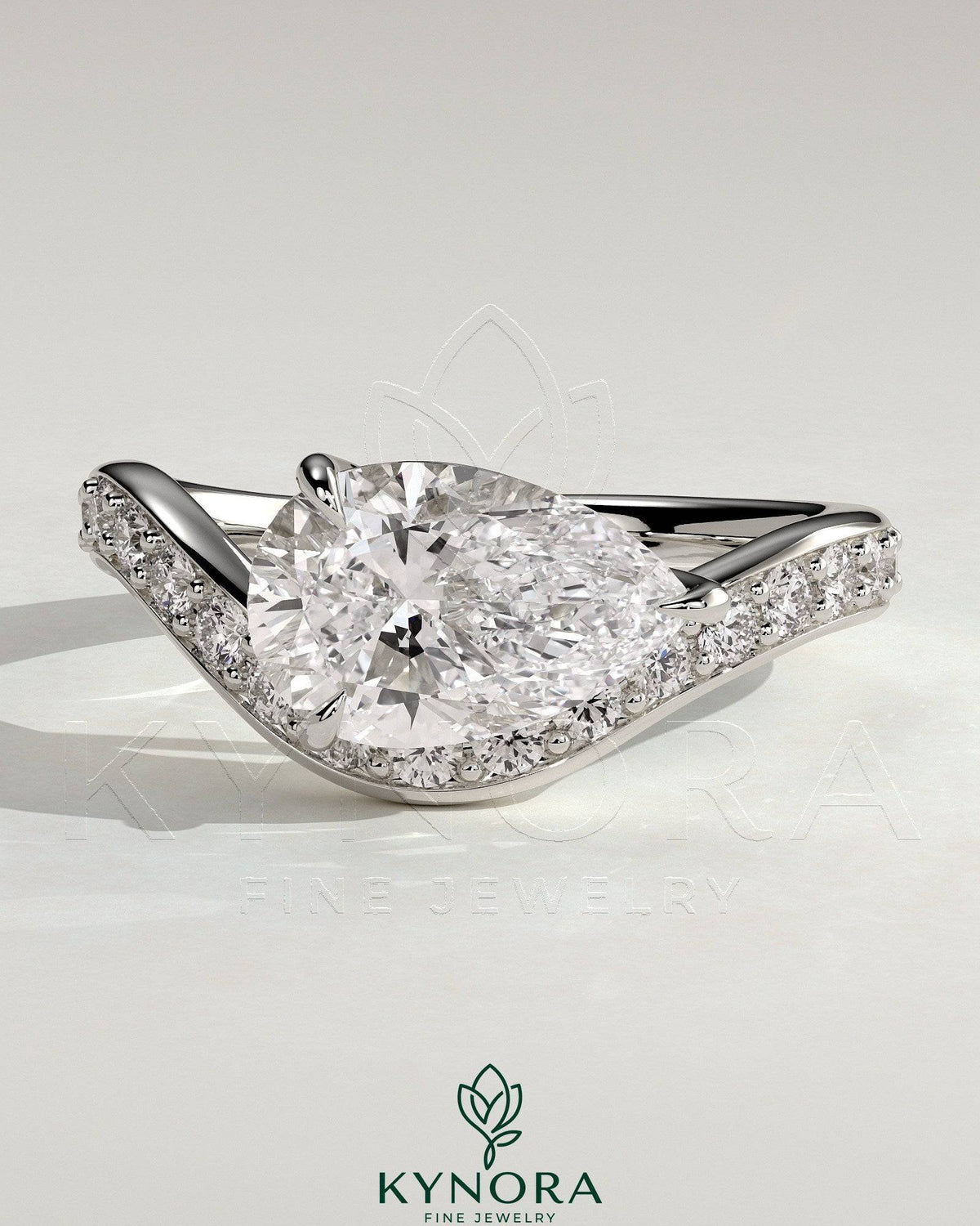 Kynora CJ 2ct pear-shaped diamond solitaire engagement ring with bead-set pave wave band in east-west setting.