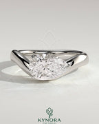 Kynora CJ 2ct pear-shaped east-west solitaire engagement ring with wave band featuring a prominent diamond in a detailed setting.
