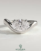 East-West 2ct oval diamond solitaire engagement ring with wave band by Kynora CJ showing the ring's design and sparkling stone.