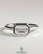 Kynora CJ statement 2ct emerald east-west bezel solitaire engagement ring with open cathedral high setting, showcasing elegant design.