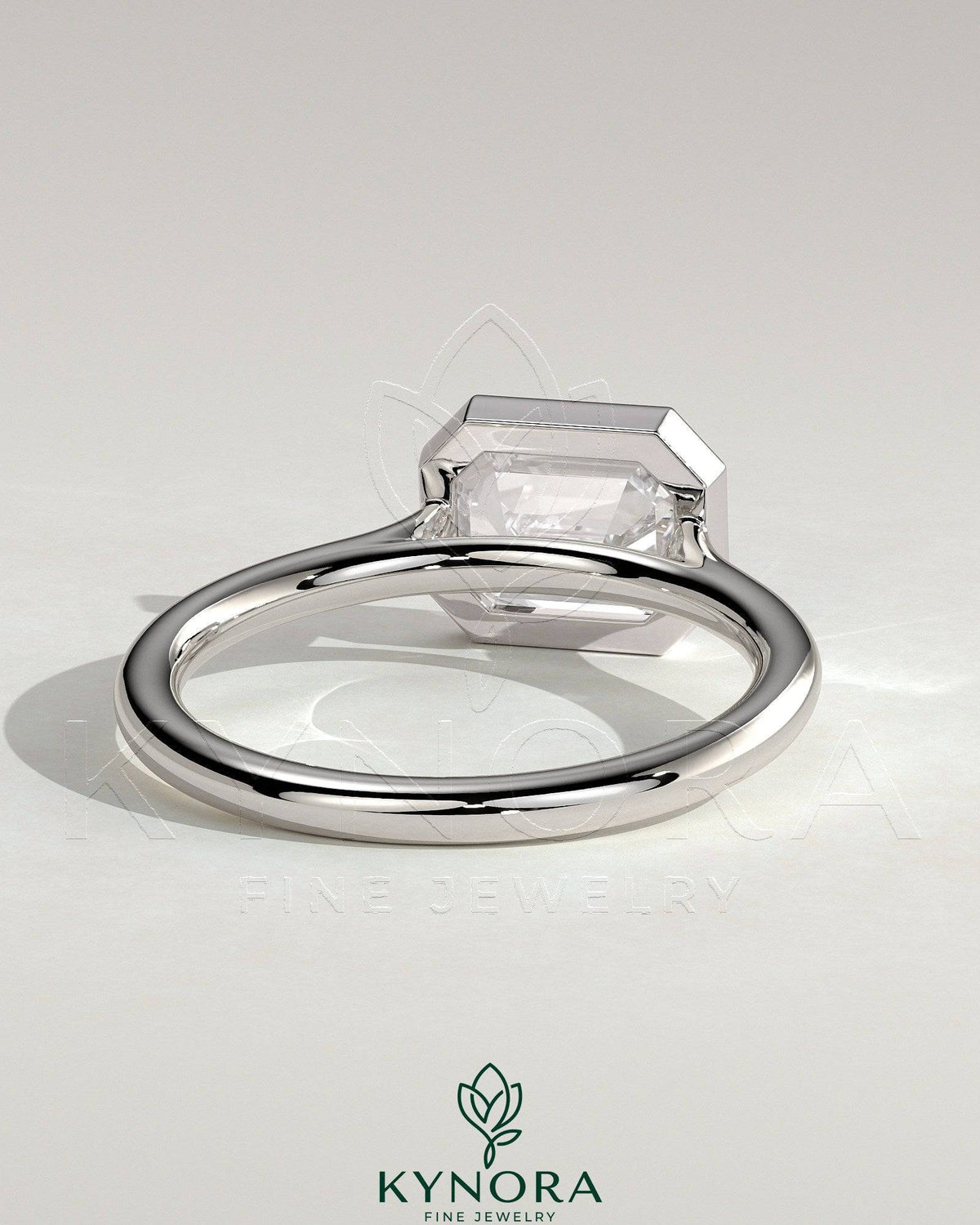 Kynora CJ emerald east-west bezel solitaire engagement ring with open cathedral high setting showcasing a 2-carat emerald gemstone.