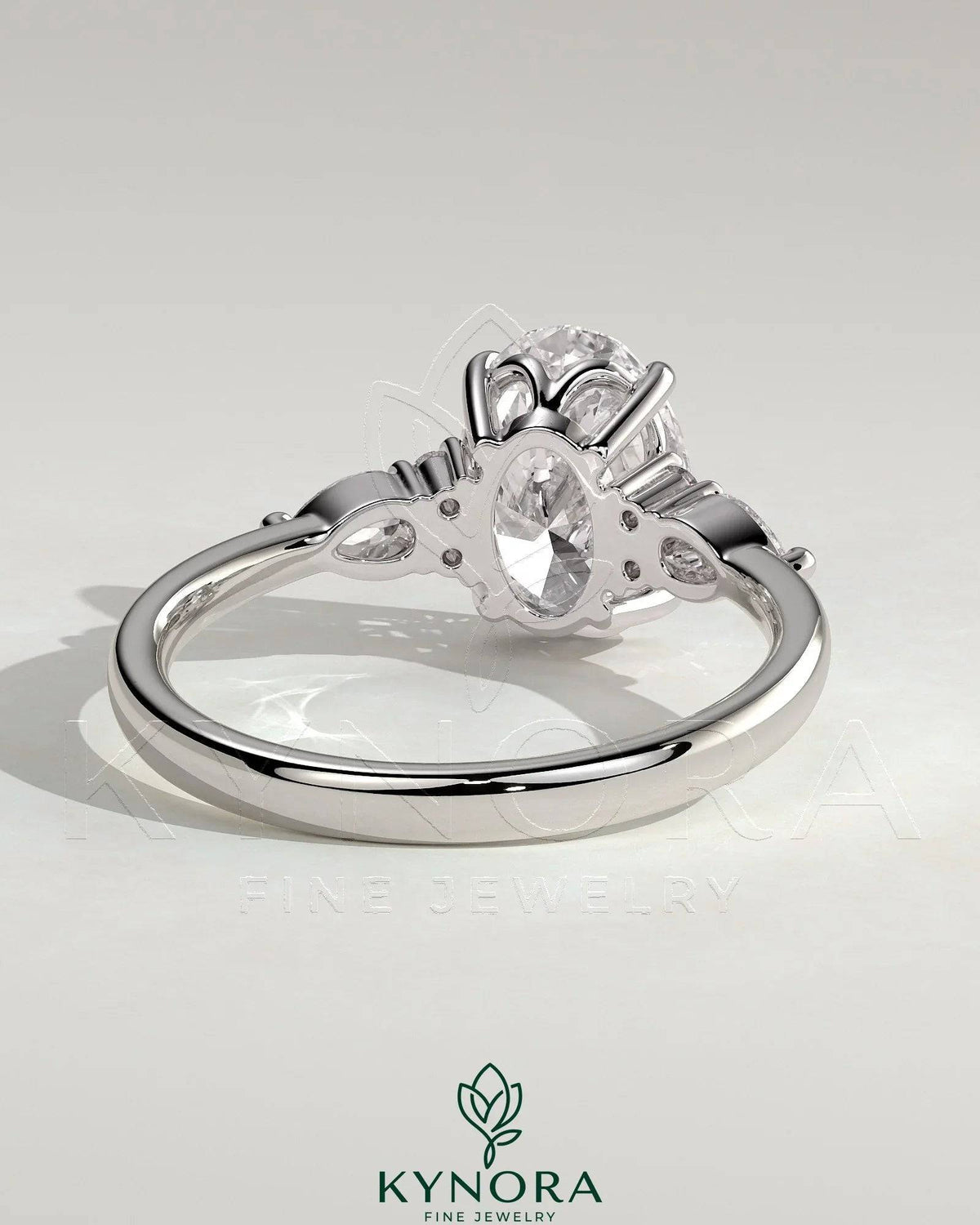 Kynora CJ 2ct oval claw solitaire engagement ring with pear-shaped accents and round shoulder stones in a three-stone design.
