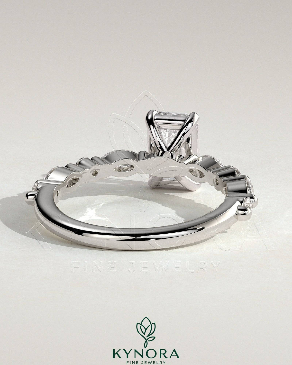 Kynora CJ 2ct emerald claw solitaire engagement ring with marquise and round accent stones, showcasing elegant jewelry design