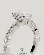 Kynora CJ 2ct emerald claw solitaire engagement ring with marquise and round accent stones, showcasing a sparkling green emerald centerpiece.