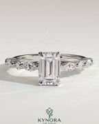 Kynora CJ 2ct emerald claw solitaire engagement ring with marquise and round accent stones, featuring intricate design and sparkling gemstones.
