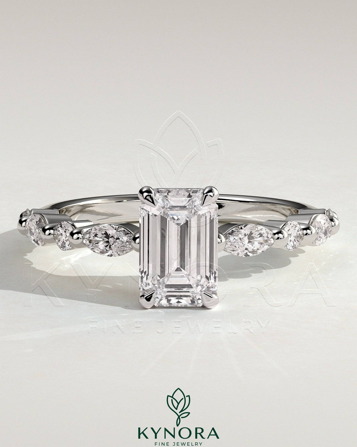 Kynora CJ 2ct emerald claw solitaire engagement ring with marquise and round accent stones, featuring intricate design and sparkling gemstones.