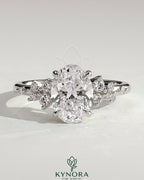 Kynora CJ 2ct oval claw solitaire engagement ring with clustered round shoulder stones, three-stone design, elegant and sparkling.