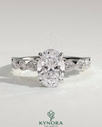 Kynora CJ 2ct oval claw solitaire engagement ring with round-marquise bezel accent stones, showcasing a sparkling elegant design