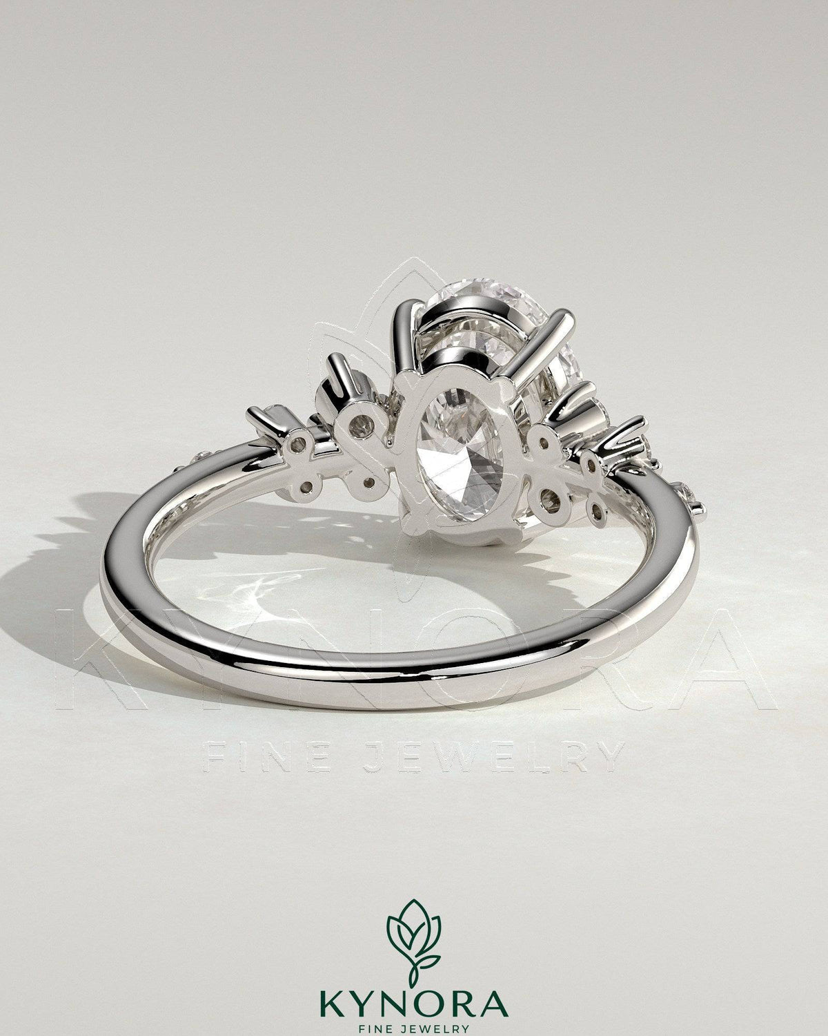 Kynora CJ 2ct oval claw solitaire engagement ring with clustered round shoulder stones, three-stone design, elegant jewelry piece.
