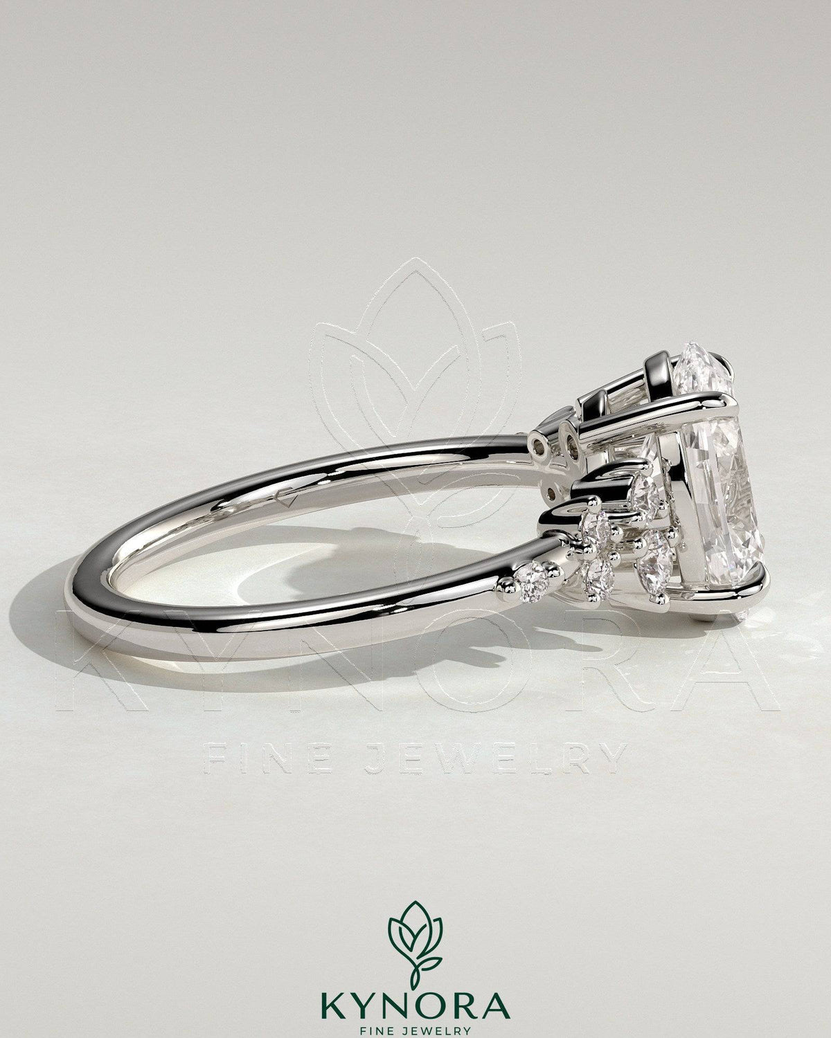 Kynora CJ three-stone engagement ring featuring a 2-carat oval claw solitaire with clustered round shoulder stones.