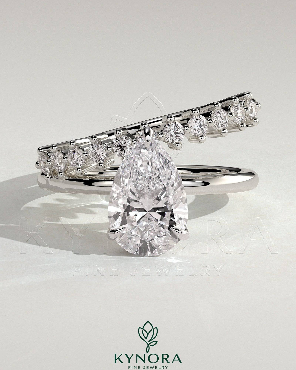 Kynora CJ 2ct pear-shaped diamond solitaire engagement ring with double plain and round accent stones on band.