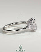 Kynora CJ 2ct oval claw solitaire engagement ring with pear-shaped accents and round shoulder stones, elegant three-stone design.