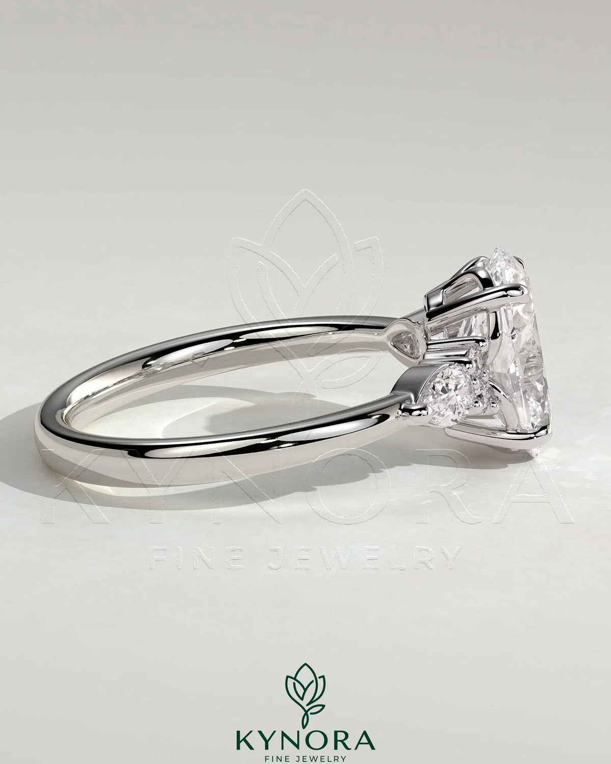 Kynora CJ 2ct oval claw solitaire engagement ring with pear-shaped accents and round shoulder stones, elegant three-stone design.