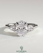 Kynora CJ 2ct oval claw trilogy engagement ring with pear side stones and cathedral setting, showcasing sparkling diamond details.