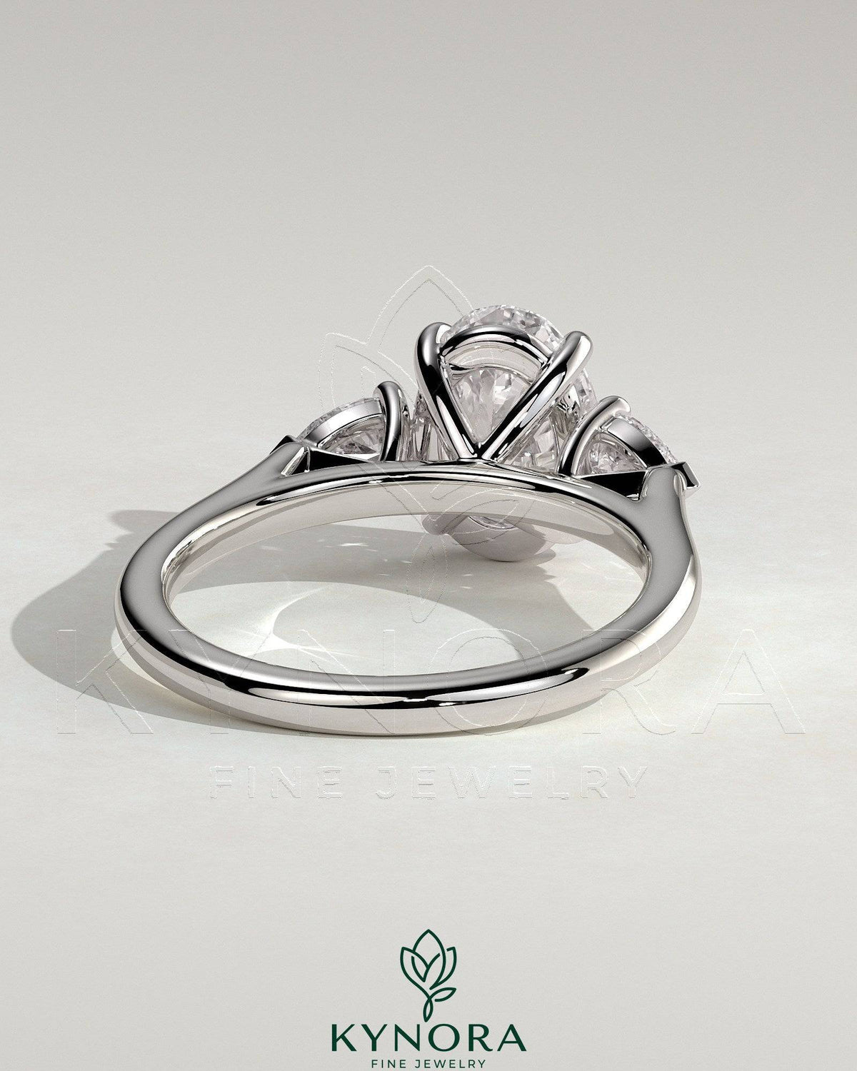 Kynora CJ three stone engagement ring featuring a 2ct oval claw trilogy center stone with pear side stones and cathedral setting.