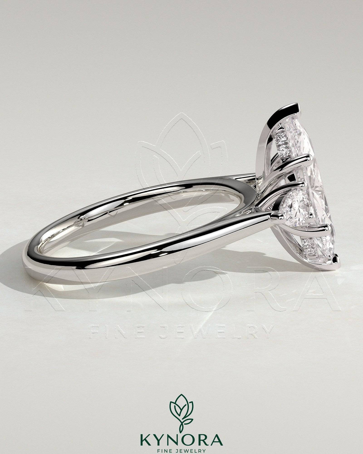 Kynora CJ 2-carat marquise claw trilogy engagement ring with pear side stones and hidden halo, showcasing elegant diamond setting.