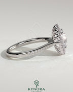 Kynora CJ 2ct round claw solitaire engagement ring with graduating halo, bead set micropave, and tapered band.