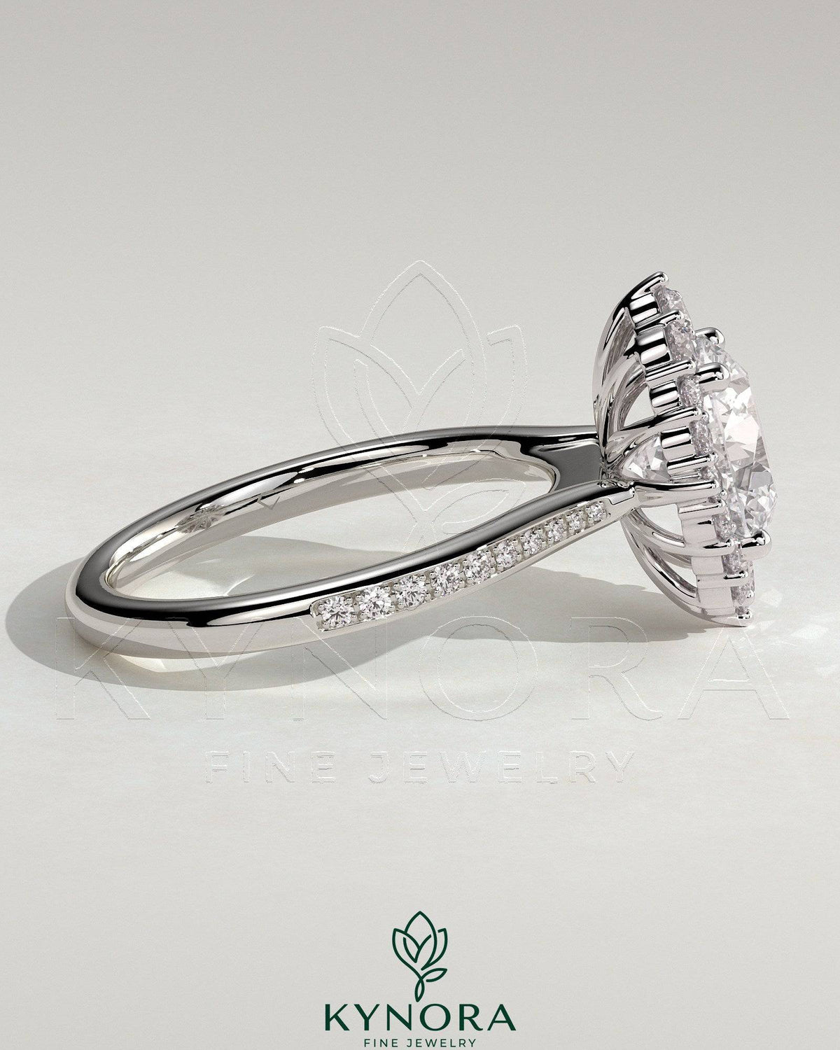 Kynora CJ 2ct round claw solitaire engagement ring with graduating halo, bead set micropave, and tapered band.