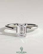 Kynora CJ 2ct emerald claw solitaire engagement ring with a wrap-around hidden halo setting, featuring a sparkling emerald center stone.
