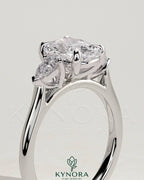 Kynora CJ 2ct elongated cushion cut trilogy engagement ring with pear side stones and cathedral setting, showcasing detailed craftsmanship.