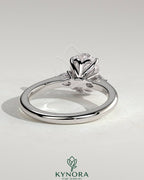 Kynora CJ 2ct oval claw trilogy engagement ring with pear side stones and tulip detail, showcasing elegant jewelry design.
