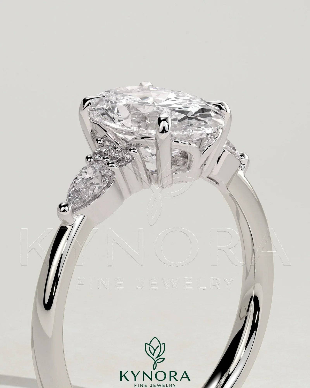 Kynora CJ 2ct oval claw solitaire engagement ring with pear-shaped accents and round shoulder stones in a three-stone design.