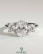 Kynora CJ 2ct oval claw trilogy engagement ring with round side stones, open trellis gallery, tapered band, three stone design
