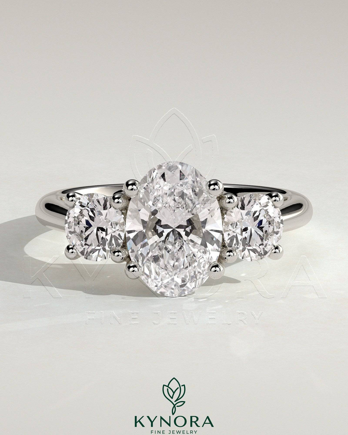 Kynora CJ 2ct oval claw trilogy engagement ring with round side stones, open trellis gallery, tapered band, three stone design