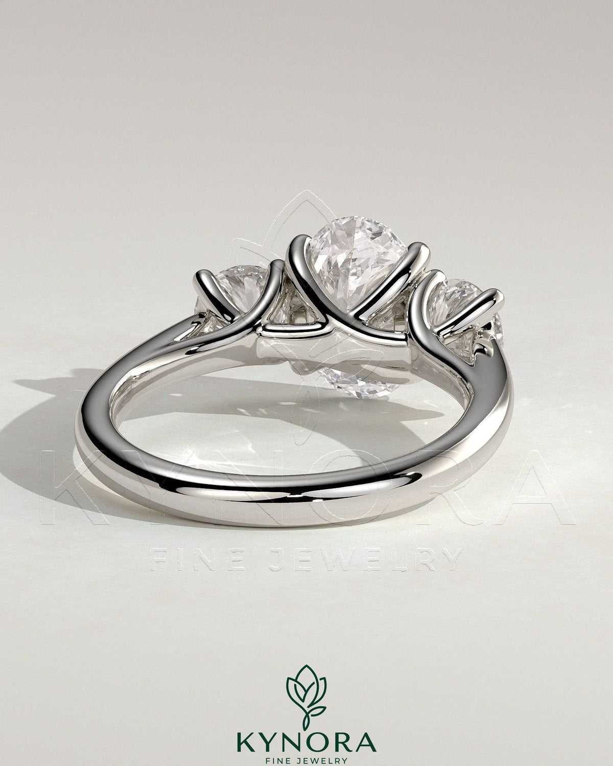 Kynora CJ 2ct oval claw trilogy engagement ring with round side stones, open trellis gallery, tapered band, and intricate design.
