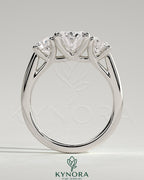 Kynora CJ 2ct oval claw trilogy engagement ring with round side stones, open trellis gallery, tapered band, three-stone design.