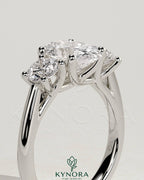 Kynora CJ 2ct oval claw trilogy engagement ring with round side stones, open trellis gallery, tapered band, elegant three stone design