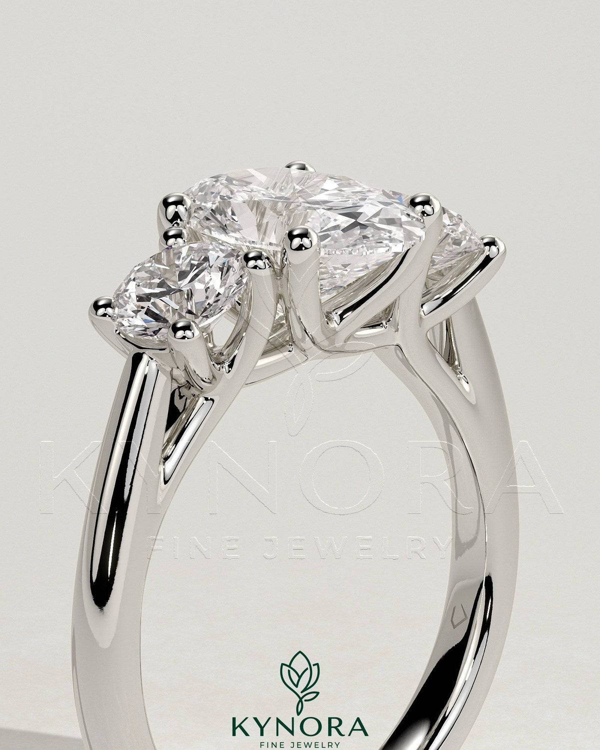 Kynora CJ 2ct oval claw trilogy engagement ring with round side stones, open trellis gallery, tapered band, elegant three stone design
