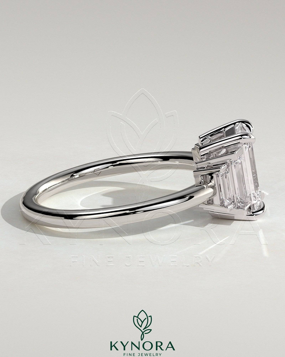 Kynora CJ 2ct emerald claw trilogy engagement ring with graduating baguette shoulder stones, elegant three-stone design.