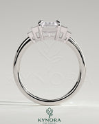 Kynora CJ 2ct emerald claw trilogy engagement ring with graduating baguette shoulder stones, three-stone design in platinum setting.