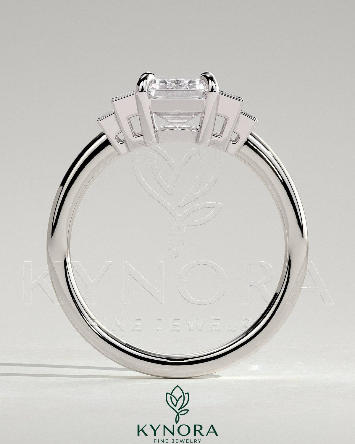 Kynora CJ 2ct emerald claw trilogy engagement ring with graduating baguette shoulder stones, three-stone design in platinum setting.