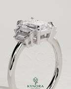 Kynora CJ 2ct emerald claw trilogy engagement ring with graduating baguette shoulder stones, elegant three-stone design.