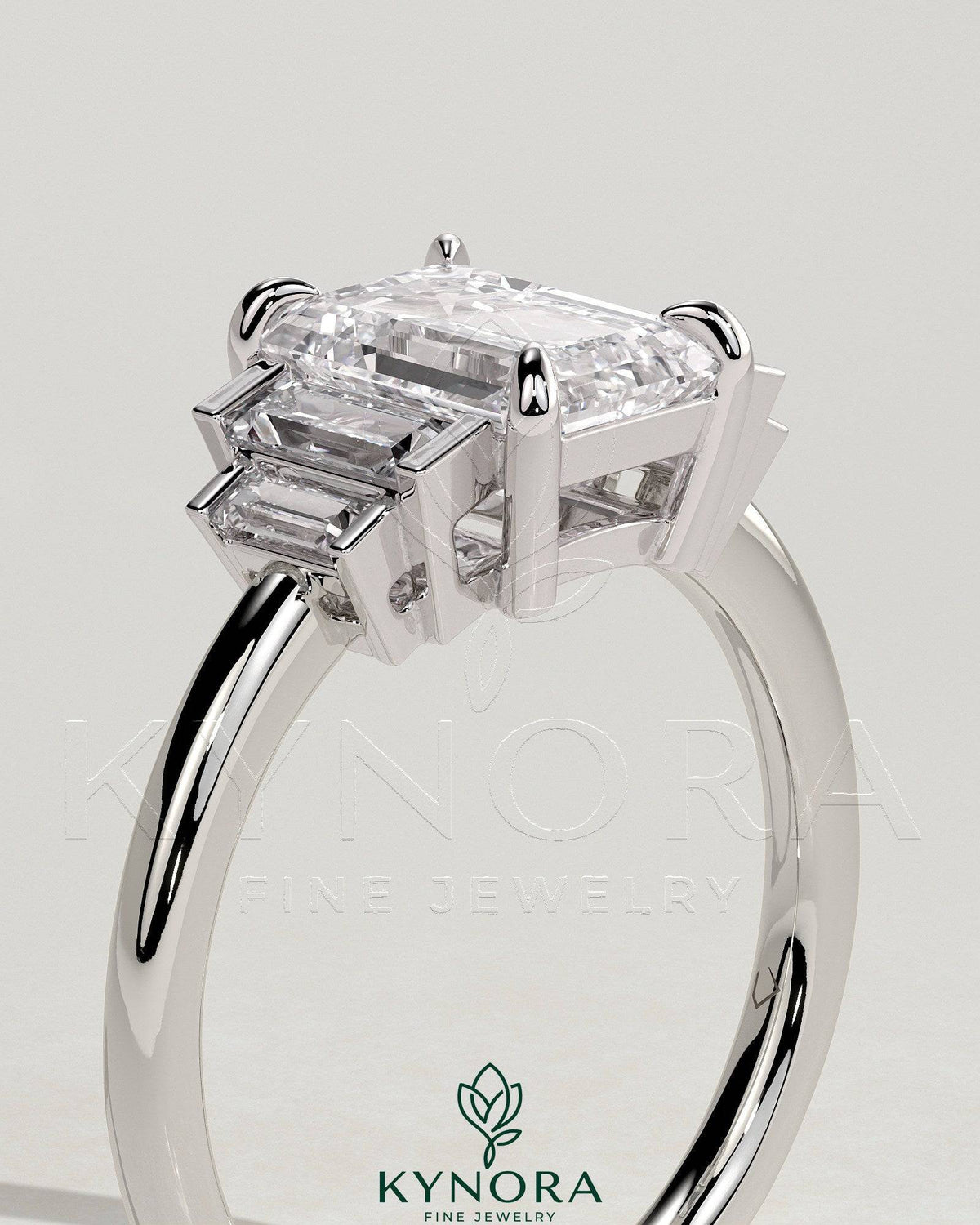Kynora CJ 2ct emerald claw trilogy engagement ring with graduating baguette shoulder stones, elegant three-stone design.