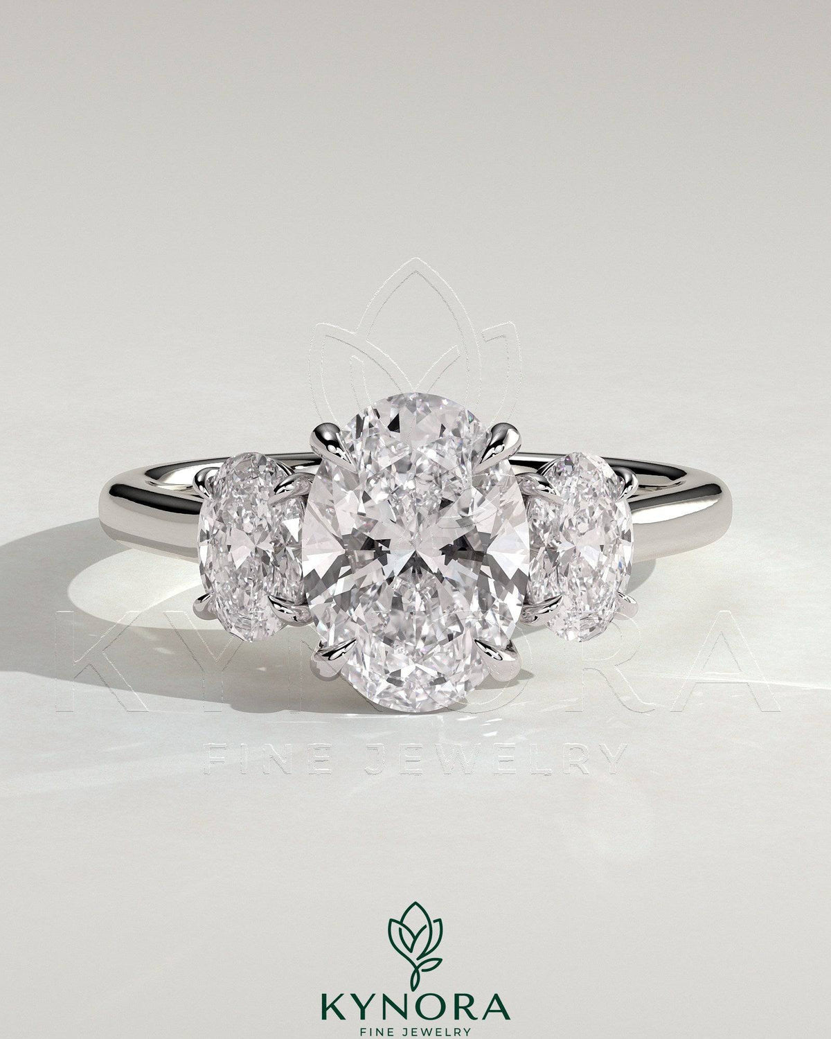 Kynora CJ 2ct oval claw trilogy engagement ring with oval side stones, showcasing a sparkling three-stone design. Imagen principal del producto