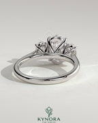 Kynora CJ 2ct oval claw trilogy engagement ring featuring oval side stones, elegant three-stone design with sparkling diamond accents.
