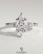 Kynora CJ three-stone engagement ring with 2ct marquise claw solitaire, pear accents, and round shoulder stones.